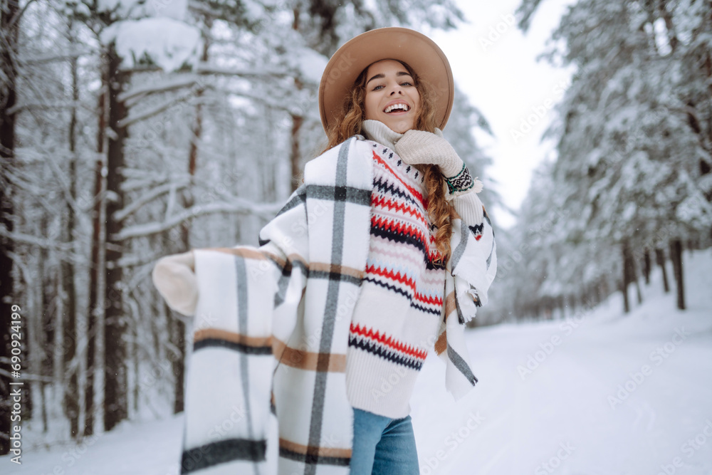 Young beautiful woman dressed in a fur coat, scarf, hat posing in the winter forest. Happy female tourist posing outdoors. Christmas.