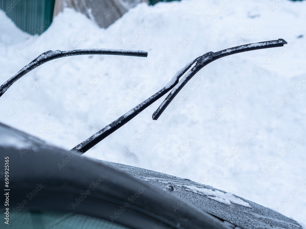 Windshield of car is covered with light snow and wipers are raised from glass Windshield of car is covered with light snow and wipers are raised from glass