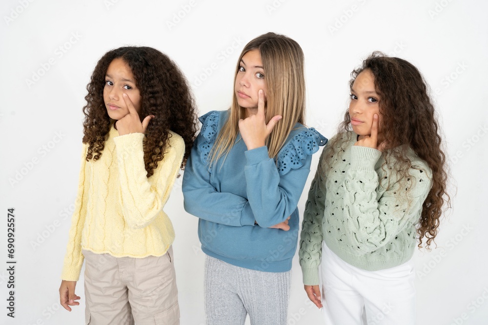 Three beautiful multiracial kid girls Pointing to the eye watching you gesture, suspicious expression. Three beautiful multiracial kid girls Pointing to the eye watching you gesture, suspicious expression.