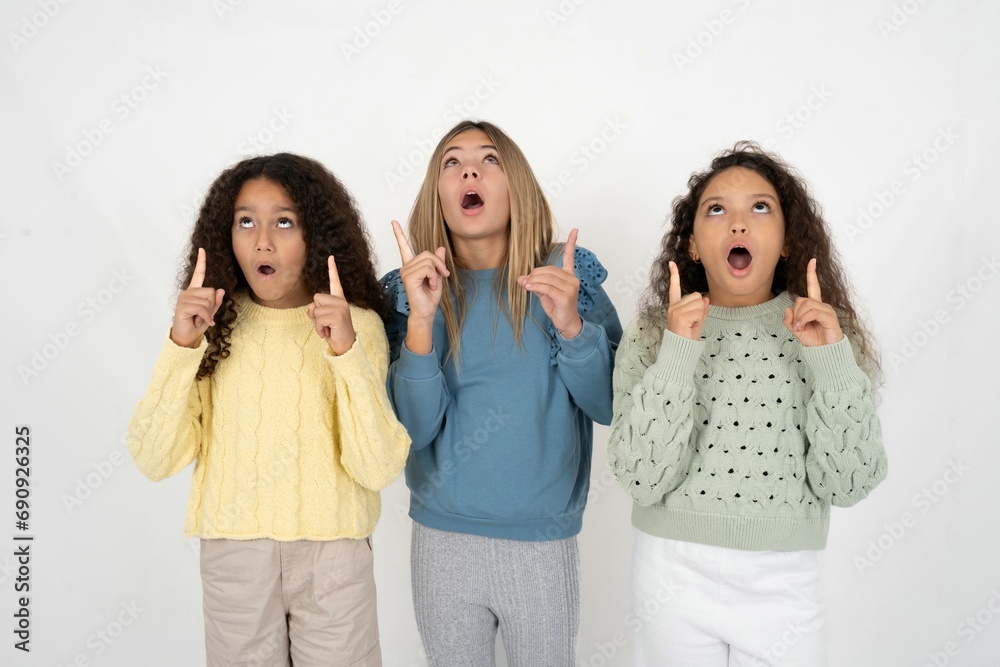 beautiful multiracial kid girls amazed and surprised looking up and pointing with fingers and raised arms. beautiful multiracial kid girls amazed and surprised looking up and pointing with fingers and raised arms.