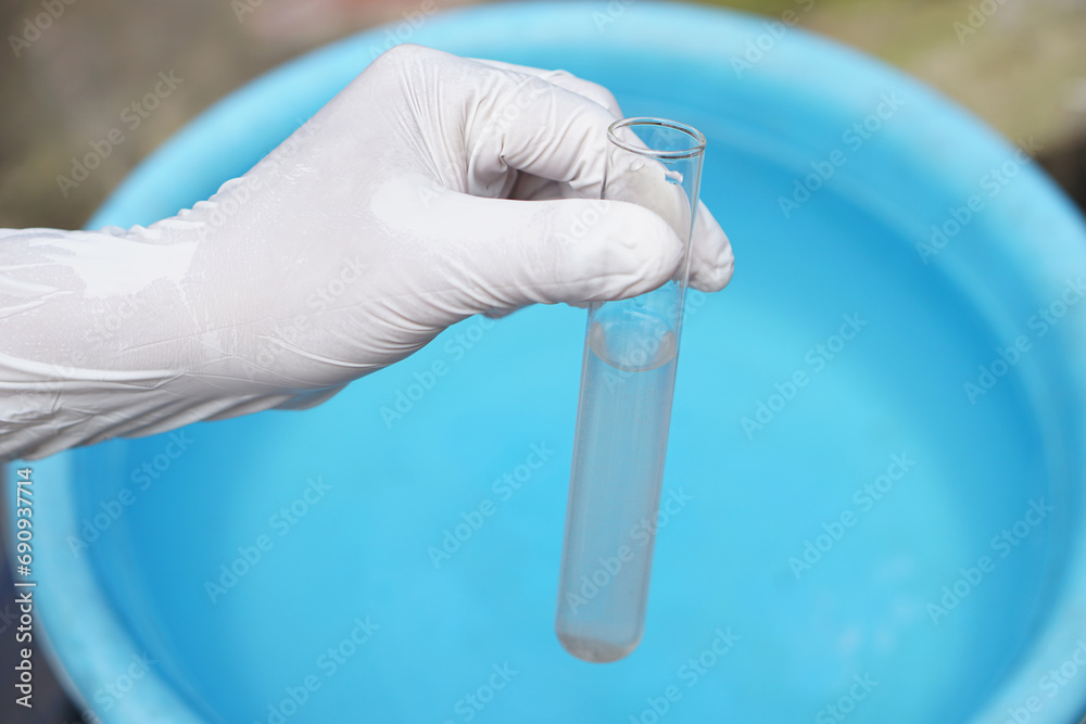 Close up ecologist hand wears glove holds test tube of water. Concept, Inspecting water quality from nature source that use in daily life. Examination water pollution. Environment Close up ecologist hand wears glove holds test tube of water. Concept, Inspecting water quality from nature source that use in daily life. Examination water pollution. Environment