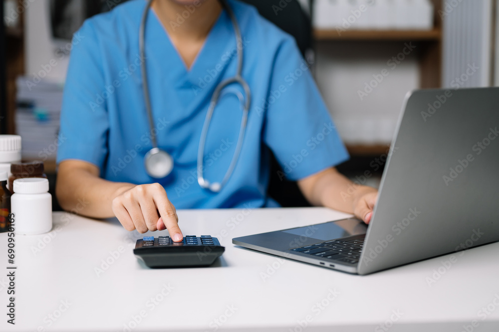 Healthcare costs and fees concept.Hand of smart doctor used a calculator and smartphone, tablet for medical costs at hospital . Healthcare costs and fees concept.Hand of smart doctor used a calculator and smartphone, tablet for medical costs at hospital .