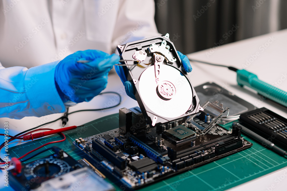Obraz premium Hard disk drive on the technician's desk and a computer motherboard as a component. the concept of data, hardware, and information technology...