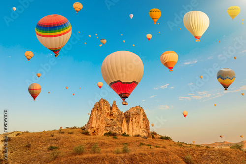 At dawn in Turkey, Cappadocia's air balloons fill the Rose Valley of Goreme with a colorful and enchanting display, a harmonious fusion of nature's beauty and human innovation for touristic trips.