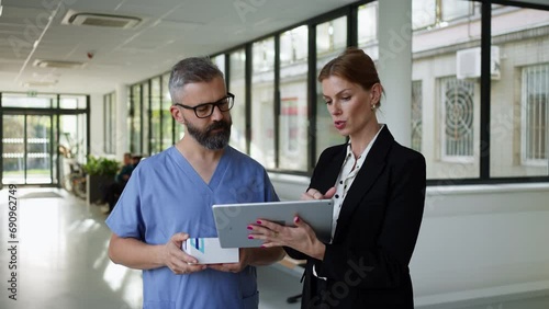 Pharmaceutical sales representative talking with doctor in medical building. Ambitious hospital director consulting with healtcare staff. Woman business leader. photo