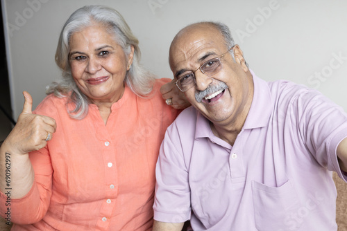 indian senior couple taking selfie with phone at living room, Retired life concept
