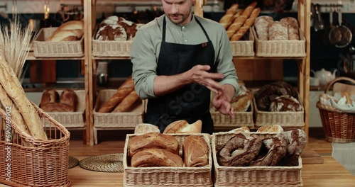 A charismatic young male baker lays out freshly baked bread.