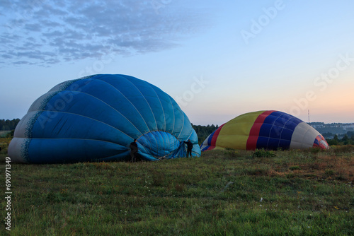A group of men prepare a hot air balloon for flight using a gas burner and a fan. #690971349