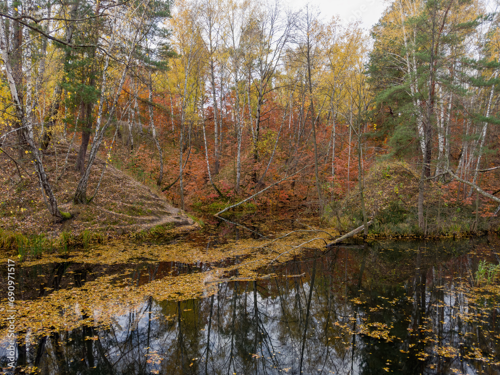 Small forest lake with hilly banks in overcast autumn morning Small forest lake with hilly banks in overcast autumn morning