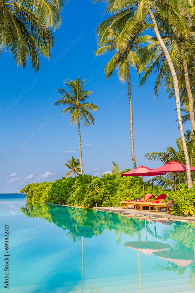 Relax tourism landscape. Luxurious beach resort with swimming pool and beach chairs or loungers leisure lifestyle, under umbrellas, palm trees, blue sky. Summer travel and vacation background concept
