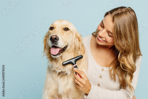 Foto Young fun owner woman wear casual clothes hug cuddle best friend retriever dog hold grooming brush trimming isolated on plain pastel light blue background studio portrait