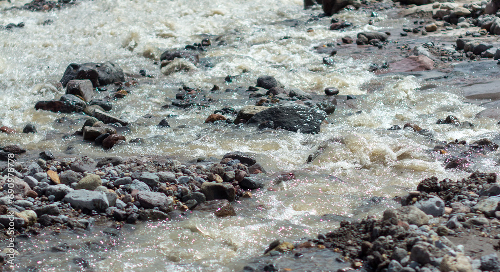 Close up of rapid waters in the Colca River, Colca Canyon, Peru. Black rocks, stones, bubbles, foam.
