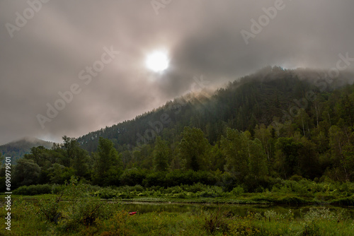 The morning sun breaks through the alot clouds over the mountains photo