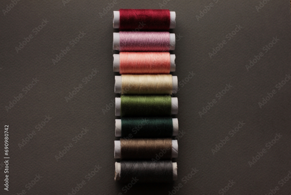 Colorful sewing threads on top of a gray cloth, top view