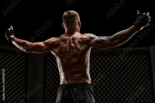 Conceptual image of a kickboxer. A real fighter stands in the real cage of the octagon. The concept of mixed martial arts, kickboxing, sports schools. Mixed media photo