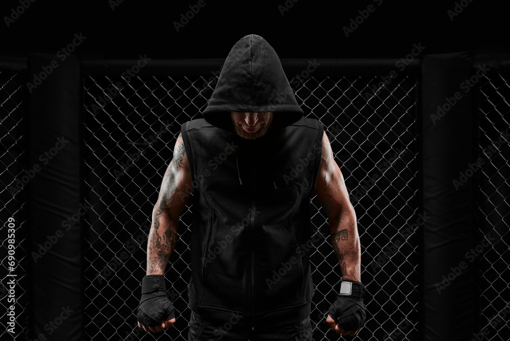 Conceptual image of a kickboxer. A real fighter stands in the real cage of the octagon. The concept of mixed idinemes, kickboxing, sports schools. - obrazy, fototapety, plakaty 