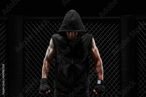 Conceptual image of a kickboxer. A real fighter stands in the real cage of the octagon. The concept of mixed idinemes, kickboxing, sports schools.