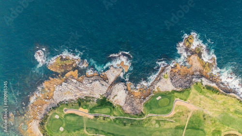 aerial aerial view from a drone towards the beach and the bay with turquoise water between the rocks and reefs of Little Bay beach in Sydney, Australia on a sunny and hot summer day.