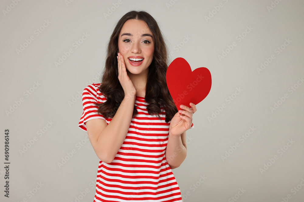 Beautiful young woman with paper heart on grey background Beautiful young woman with paper heart on grey background