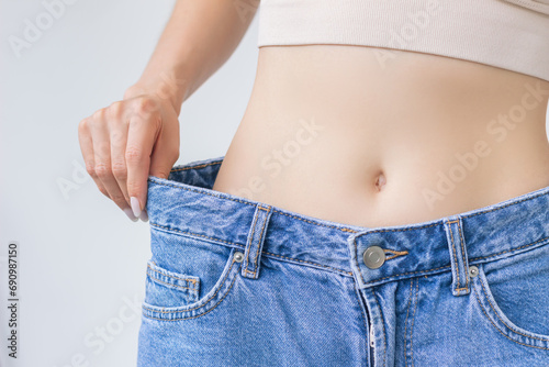 close up young woman tries on her jeans after a healthy weight loss, which turned out to be big. Healthy lifestyle and proper nutrition. The concept of weight loss.