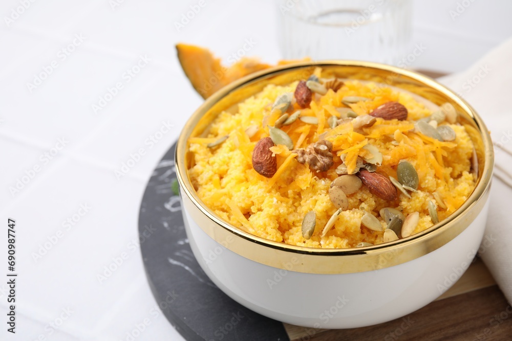Tasty cornmeal with nuts, pumpkin and seeds in bowl on white table, closeup. Space for text Tasty cornmeal with nuts, pumpkin and seeds in bowl on white table, closeup. Space for text