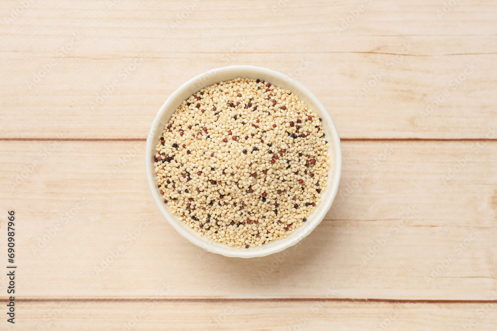 Raw quinoa seeds in bowl on wooden table, top view Raw quinoa seeds in bowl on wooden table, top view