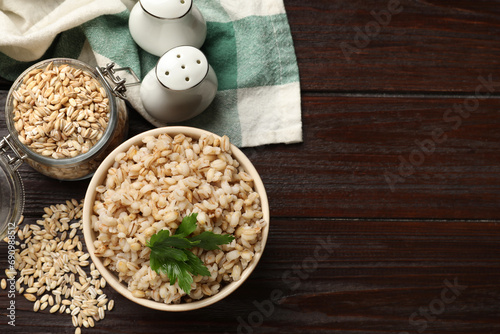 Delicious pearl barley with parsley served on wooden table, flat lay. space for text photo