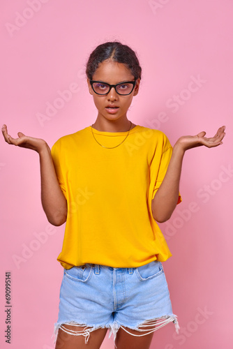 Quadro em tela Young dissatisfied Indian woman teenager spreads arms and rolls eyes looking at camera from under forehead to demonstrate contempt and disrespect for viewer stands on pink background
