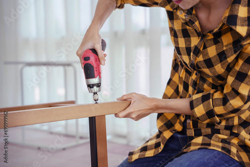 Women use electric screwdriver to installation screw and assembling chair furniture for new house