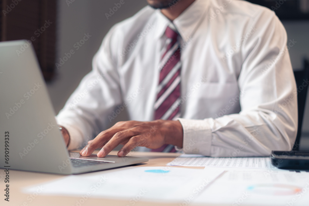 Businessman typing business report on laptop while analysis finance and accounting data of project Businessman typing business report on laptop while analysis finance and accounting data of project