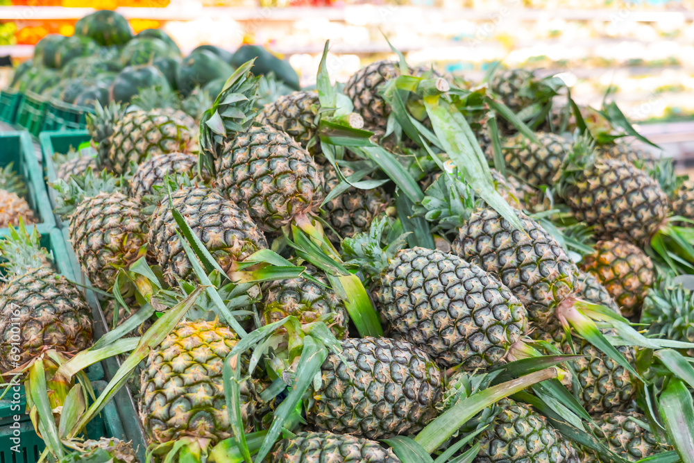 Shelf with fresh whole pineapples at grocery market. Exotic fruits from organic farms. Merchandising fruit in market buyers. Shelf with fresh whole pineapples at grocery market. Exotic fruits from organic farms. Merchandising fruit in market buyers.