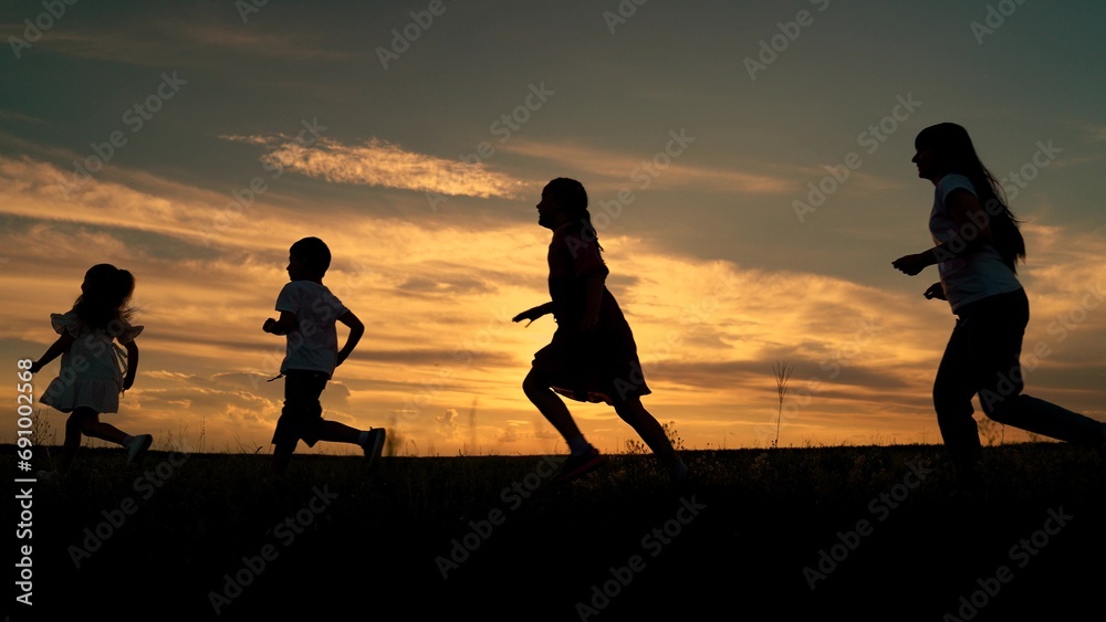 Mom dad daughter son running, children dream concept, sky. Children Mom Dad play run at sunset. Happy family dream running together in front of sun in park. People playing together in park, Silhouette