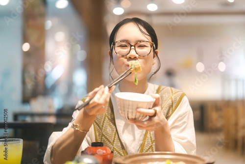 Happy asian woman holding rice bowl eating food at Japanese restaurant asia tasty from traditional culture photo