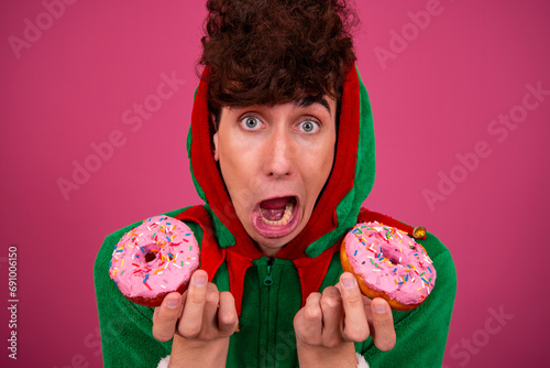 A funny guy in a New Year's costume is eating donuts. Sweet desserts and diet.
