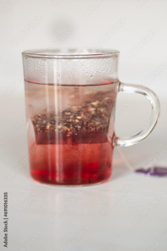 Tisane au cassis qui infuse dans une tasse transparente sur une table blanche Tisane au cassis qui infuse dans une tasse transparente sur une table blanche
