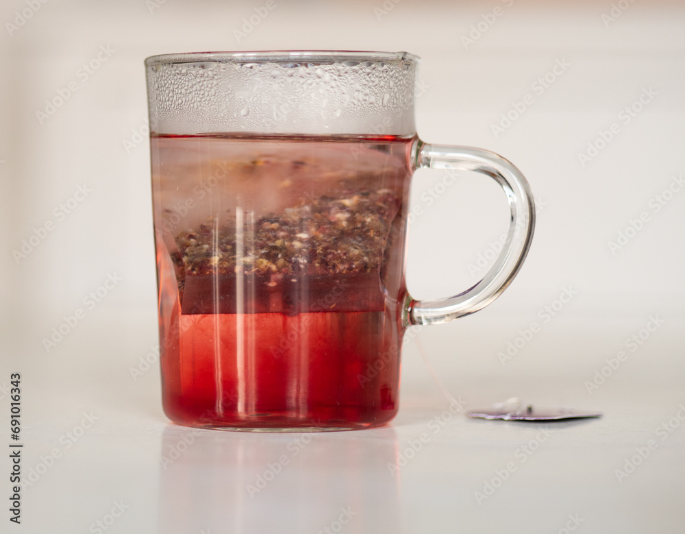 Tisane au cassis qui infuse dans une tasse transparente sur une table blanche Tisane au cassis qui infuse dans une tasse transparente sur une table blanche