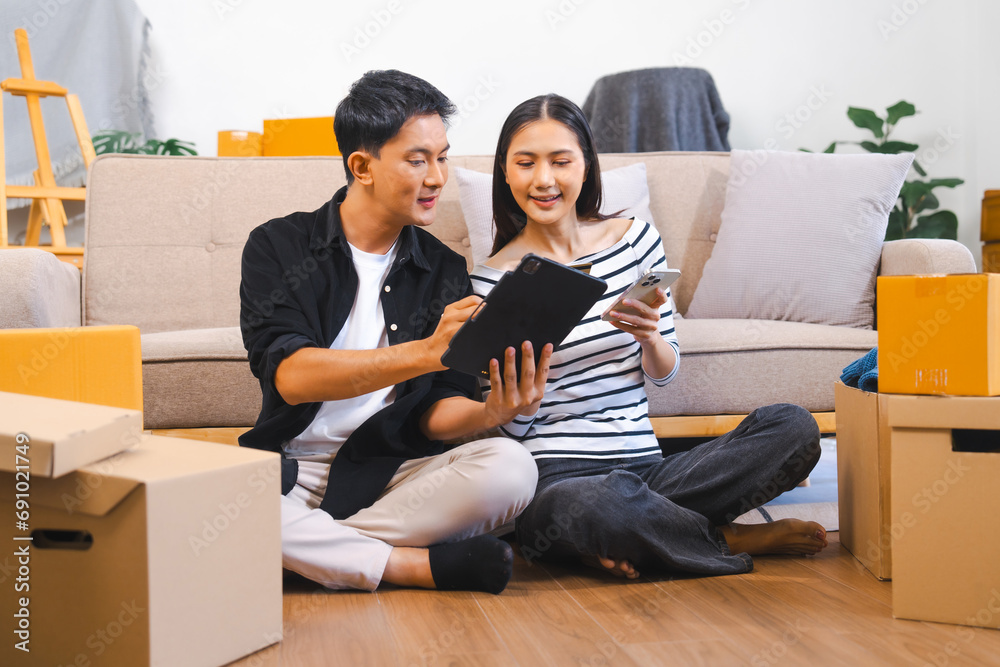 happy Asian couple unpacking boxes and sharing a moment with a blue sweater, suggesting they are moving into a new home together. happy Asian couple unpacking boxes and sharing a moment with a blue sweater, suggesting they are moving into a new home together.