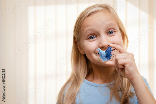 Retainer for Expansion Jaw of Children. Happy Child Little Girl holding Orthodontic Plate Teeth in Hands. Dental plate. Copy space.