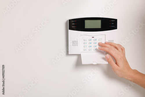 Woman entering code on home security system, closeup. Space for text