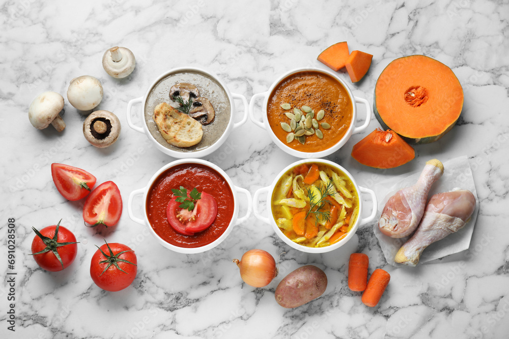 Tasty broth, different cream soups in bowls and ingredients on white marble table, flat lay Tasty broth, different cream soups in bowls and ingredients on white marble table, flat lay