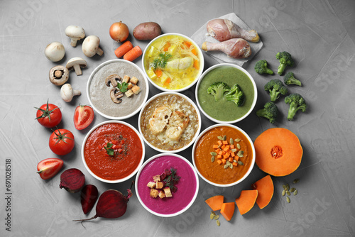 Fototapeta Naklejka Na Ścianę i Meble -  Tasty broth, different cream soups in bowls and ingredients on gray table, flat lay