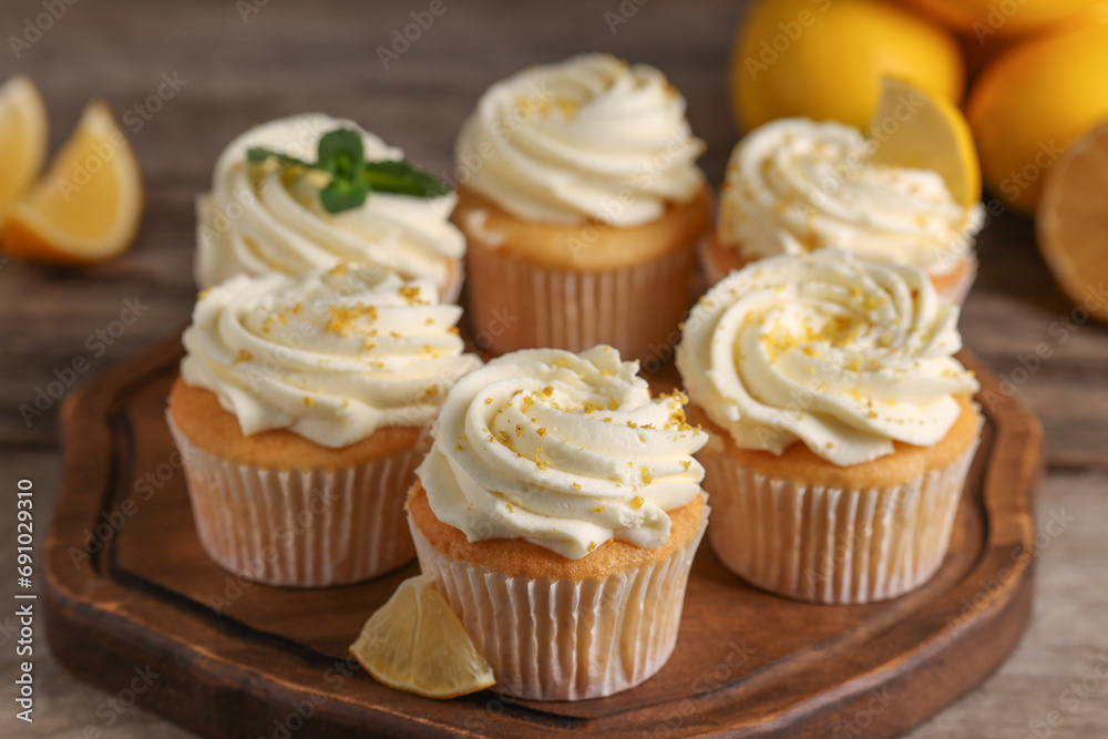 Delicious cupcakes with white cream and lemon zest on wooden table, closeup