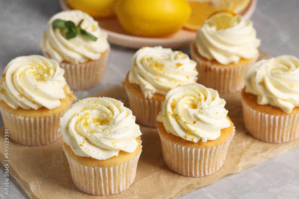 Delicious cupcakes with white cream and lemon zest on table, closeup