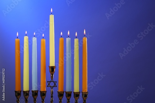 Hanukkah celebration. Menorah with burning candles on blue background  space for text