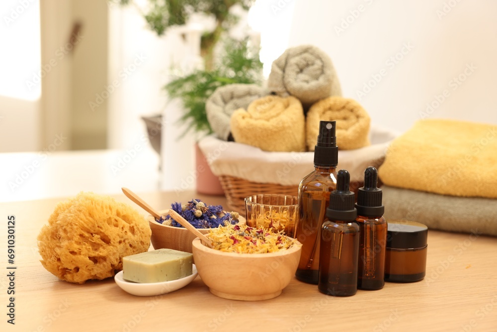 Dry flowers, loofah, soap bar, bottles of essential oils and jar with cream on wooden table indoors. Spa time