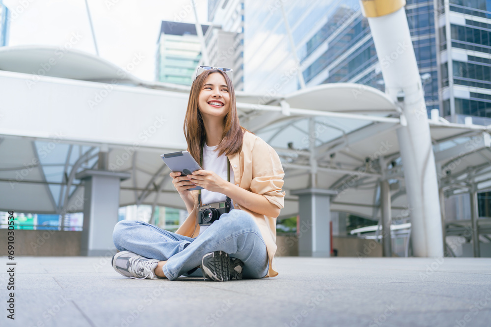 Young Asian woman sit and relax and use tablet with camera and looking for tourist attractions. Young Asian woman sit and relax and use tablet with camera and looking for tourist attractions.