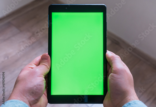 Man is holding tablet pc on his hands. Green screen mockup on the tablet. Top view.