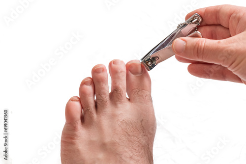 Man cuts his toenails with nail clippers. Close-up shot. Isolated white background.