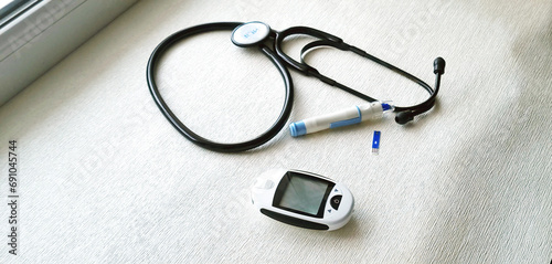 Close up shot of the glucometr instrument and stethoscope on the white surface. Healthcare