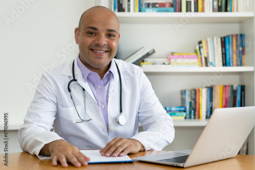 Lachender Arzt schaut in die digitale Patientenakte